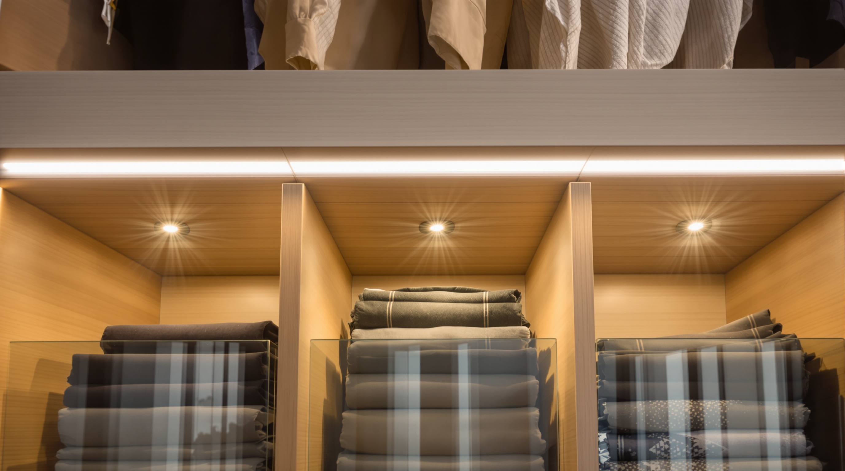 Sistema de iluminação em closet de luxo com nichos iluminados e prateleiras suspensas